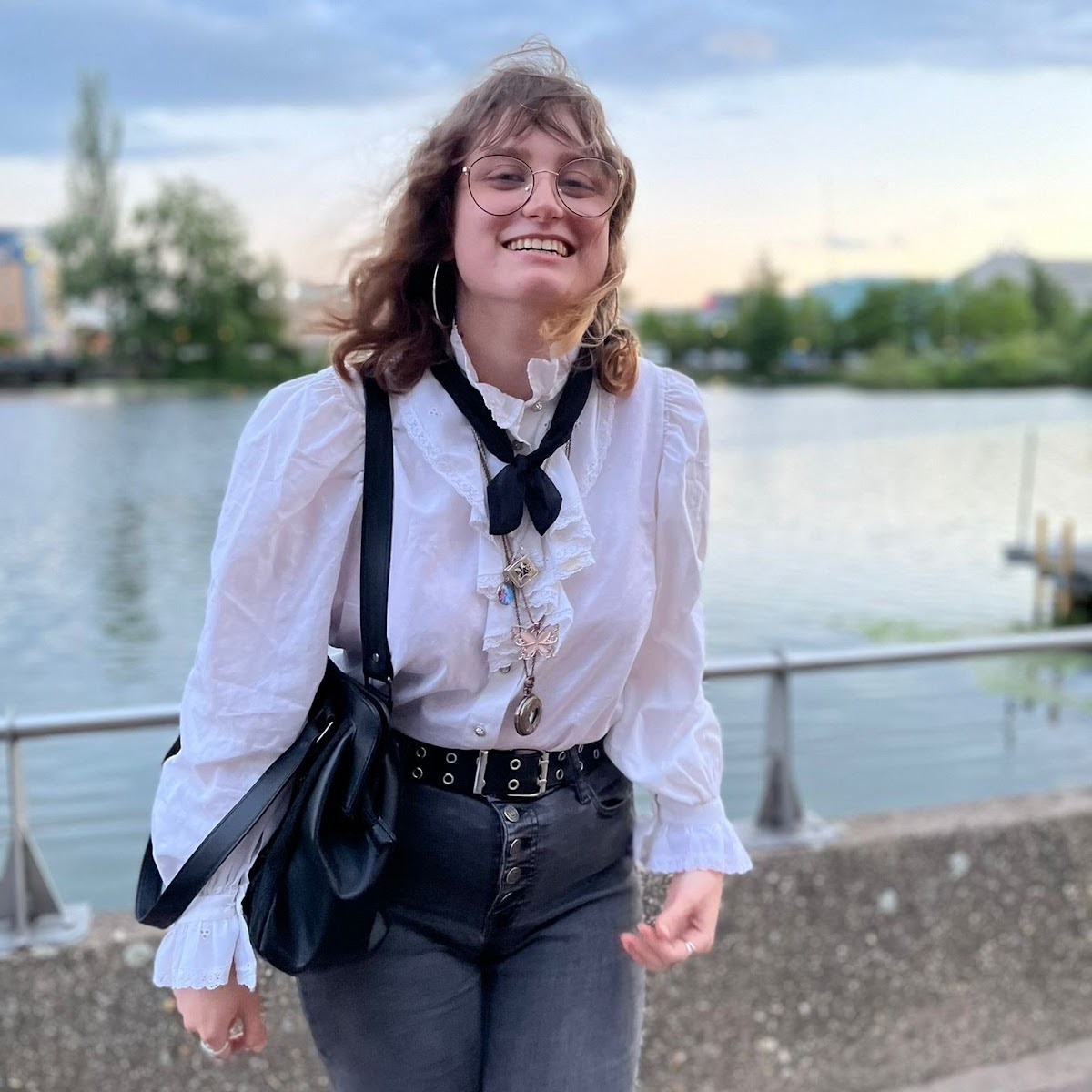 after the reading by the brayford—wind-tousled hair, white ruffled shirt, high-waisted black jeans, round glasses.